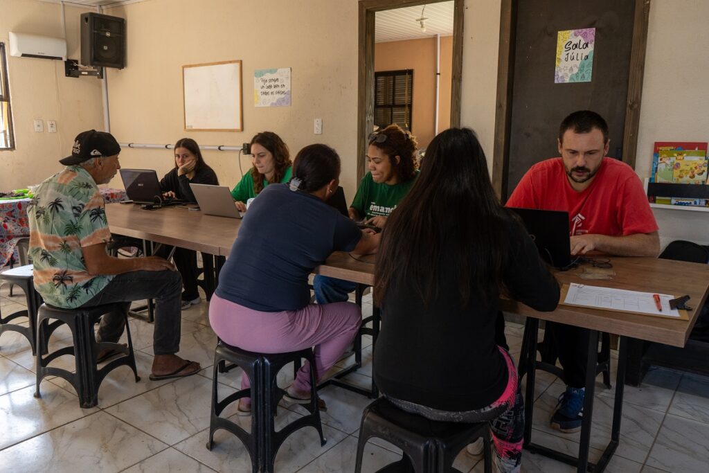 Fotos de pessoas sendo atendidas no mutirão de assessoria às famílias da Vila Dique sobre Minha Casa Minha Vida Compra Assistida