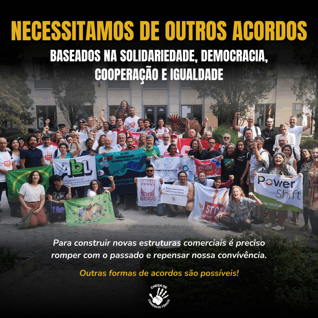 Imagem de grupo amplo reunido ao ar livre, pessoas diversas segurando faixas de organizações civis (como Jubileu Sul etc.), alguns com punho erguido em gesto de resistência. Acima, o título em amarelo: “NECESSITAMOS DE OUTROS ACORDOS”, seguido da frase “Baseados na solidariedade, democracia, cooperação e igualdade”. Abaixo, em letras menores: “Para construir novas estruturas comerciais é preciso romper com o passado e repensar nossa convivência. Outras formas de acordos são possíveis!” São visíveis árvores e ambiente urbano ao fundo.