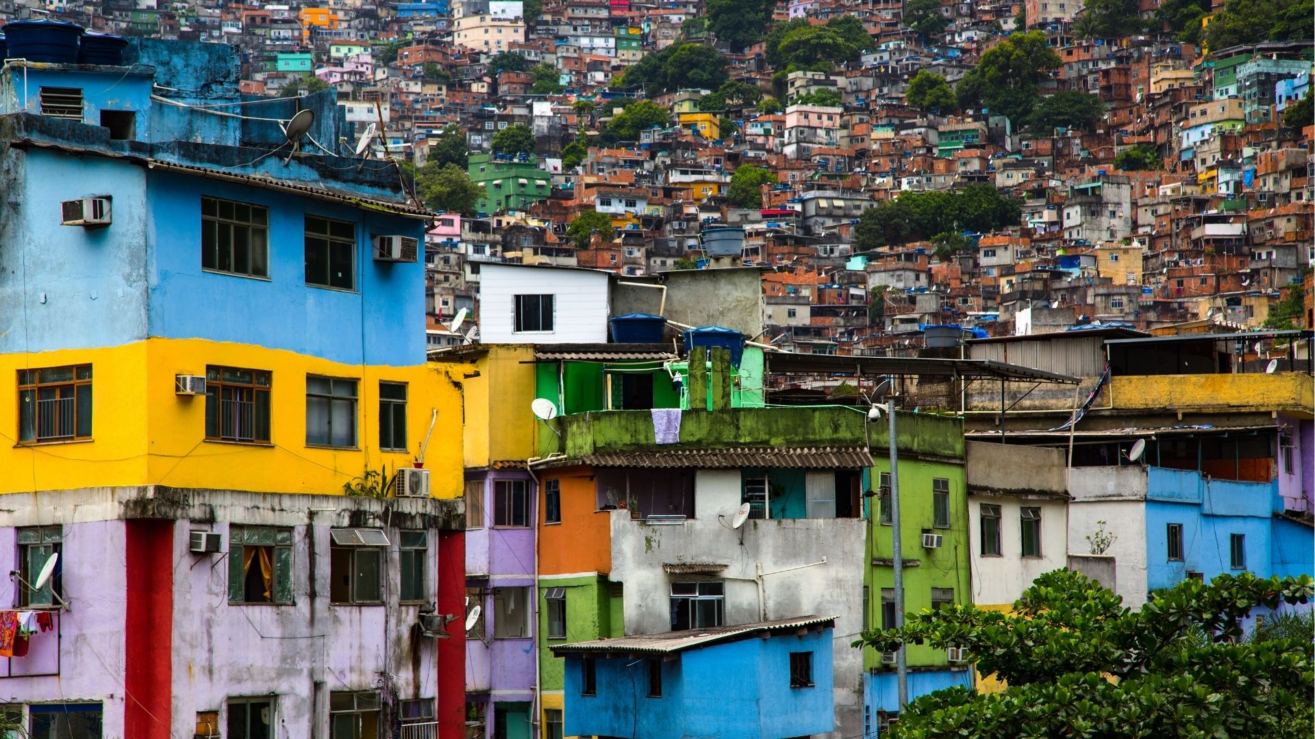 Casas coloridas e densamente agrupadas em uma favela construída sobre morro, com muitas moradias simples e próximas umas das outras ao fundo.
