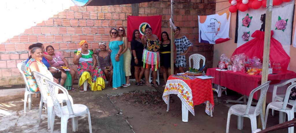 Mulheres sentadas em roda de conversa em Manaus, lendo e discutindo folhetos durante atividade comunitária.